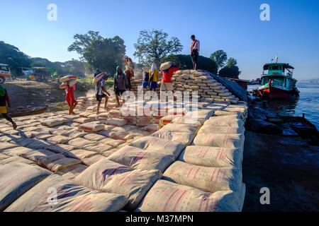 I lavoratori sono carico di sacchi di cemento su una barca in porto alla periferia della città sul fiume Irrawaddy Foto Stock