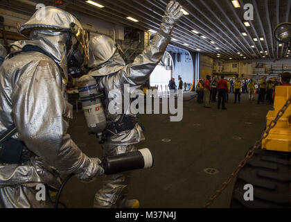 170914-N-DC385-388 Mare delle Filippine (sett. 14, 2017) Aviation BoatswainÕs Mate (manipolazione) Airman Rinaldy Desulme, destro da West Palm Beach, Florida, segnali per una scena leader come Airman David Schwengels, sinistra, da Footville, Wis., sorge da con un estintore ad anidride carbonica durante un aeromobile drill incendio in un hangar bay dell'assalto anfibio nave USS Bonhomme Richard (LHD 6). Bonhomme Richard, ammiraglia del Bonhomme Richard Expeditionary Strike gruppo, è operativo in Indo-Asia-regione del Pacifico per rafforzare le partnership e di essere una pronta risposta in vigore per qualsiasi tipo di emergenza. (U.S. Foto Stock