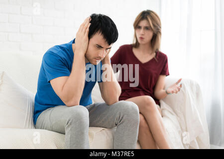 Giovane aventi argomento conflitto, cattive relazioni. Arrabbiato furia urlando donna uomo vicino le sue orecchie in casa. Foto Stock