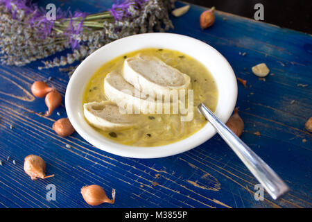 Tradizionale Zuppa francese di cipolle con crostini. Blu sulla tavola di legno con lavanda e bulbi Foto Stock
