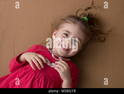 Chiusa-up ritratto di allegro bambina sullo sfondo di una scatola di cartone Foto Stock