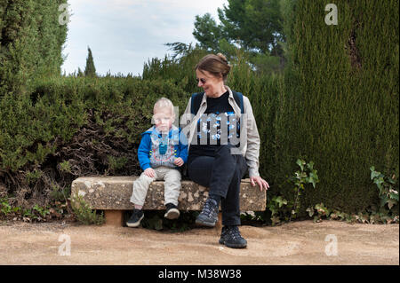Donna con il suo nipote seduta su una panchina di pietra nel giardino di Antequera il castello (Alcazaba), provincia di Malaga, Andalusia, Spagna, Europa Foto Stock