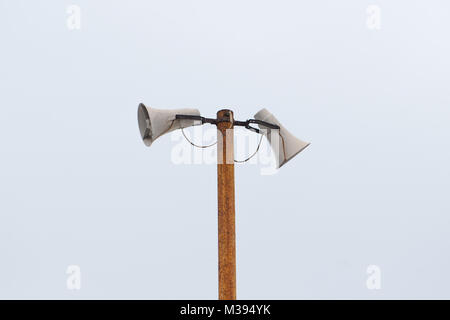 Vecchio bianco esterno altoparlanti, megafoni su un metallo arrugginito pole. Foto Stock