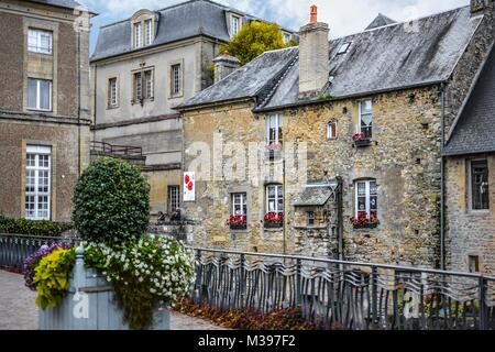 Pittoresca piazza nel villaggio storico di Bayeux in Francia con le case di pietra e finestre con fiori colorati in scatole Foto Stock