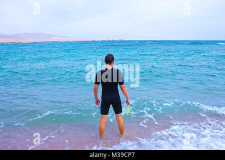 Giovane uomo nella muta va al mare in estate all'aperto Foto Stock