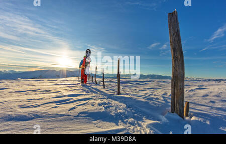 Backview di snowboarder passeggiate con le racchette da neve in polvere di neve. Unione scenario alpino, sport invernali e attività Foto Stock