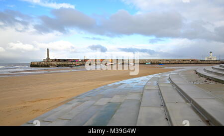 La spiaggia con la bassa marea dal tempestoso e ventoso con Margate braccio del porto in background, Margate, Kent, Regno Unito Foto Stock