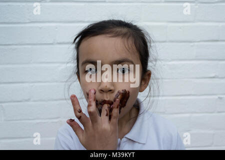 Bambino mangiare il cioccolato con il disordine sulla faccia Foto Stock