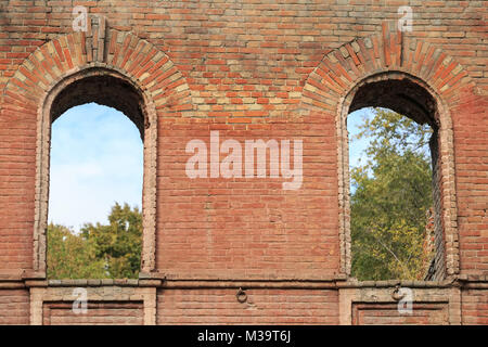 Due attraverso la finestra cannoniere nel vecchio muro di mattoni di una casa antica Foto Stock