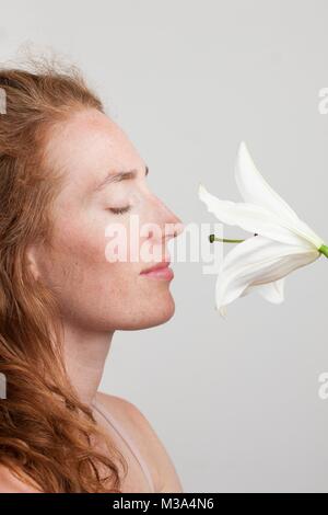 Modello rilasciato. Profilo di giovane donna con i capelli rossi profumati fiori bianchi. Foto Stock