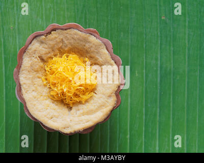 Thai dessert, budino con dolci di riso appiccicoso e rabboccato con fili dorati, sulla banana leaf background Foto Stock
