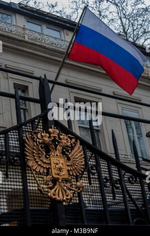 Febbraio 10, 2018 - Londra, Regno Unito. Il 10 febbraio 2018. La bandiera russa fliesw al di sopra di l'aquila sui cancelli dell'Ambasciata russa come manifestanti attraverso la strada accusano la Russia di crimini di guerra in Siria e dire loro di lasciare il paese. La protesta organizzata dalla Siria Campagna di Solidarietà è venuto dopo alcuni dei più grandi massacri poiché l'attacco chimico dello scorso aprile, uccidendo le donne e i bambini in Idlib dove ci sono continuati ampiamente riportati gli attacchi chimici e bombardamenti mirati a ospedali e squadre mediche di soccorso. La recente ondata di attacchi segue il tiro giù di un russo getto su Idlib da Foto Stock