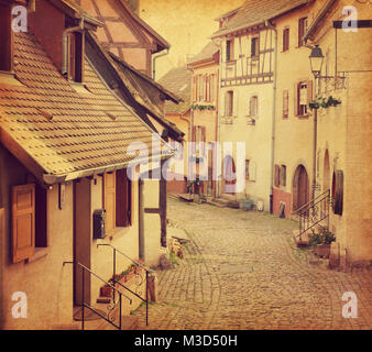 Strada di avvolgimento in Eguisheim, Francia nord-orientale. La foto in stile retrò. Aggiunta di Grana carta. Immagine dai toni Foto Stock