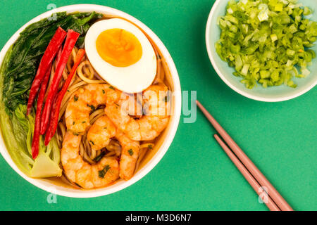 Stile giapponese di gamberi e Noodle Ramen zuppa con pak choi e peperoncino contro uno sfondo verde Foto Stock