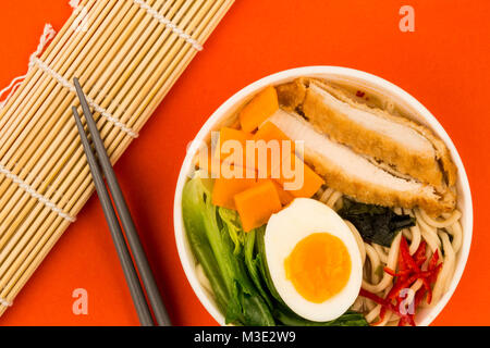 In stile giapponese pangrattato Panko e pollo Brodo di pasta o minestra di patate dolci contro uno sfondo rosso Foto Stock