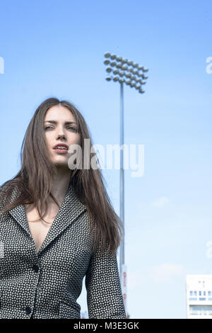 Una bella ragazza che indossa un tailored elegante abito modellato è a Cricket Ground su una bella giornata splendente- lei è fiducioso e assertivi Foto Stock