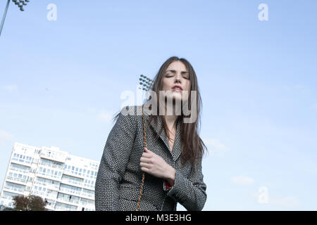 Una bella ragazza che indossa un tailored elegante abito modellato è a Cricket Ground su una bella giornata splendente- lei è fiducioso e assertivi Foto Stock