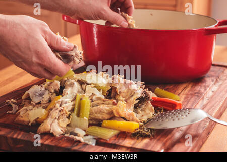 Separare la carne dalle ossa dopo la bollitura avanzi di pollo arrosto carcasse. La carne viene poi inserito nuovamente nella pentola di zuppa. Foto Stock