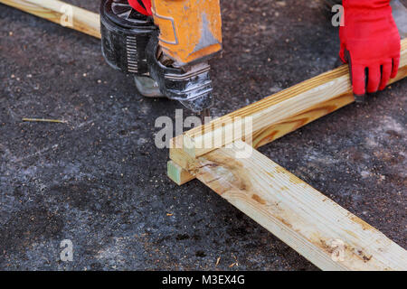 Contraente maschio lavora con asse di legno e la fresa sul pavimento. Close-up di maturo artigiano le mani in guanti di protezione con la creazione di strumenti. Foto Stock