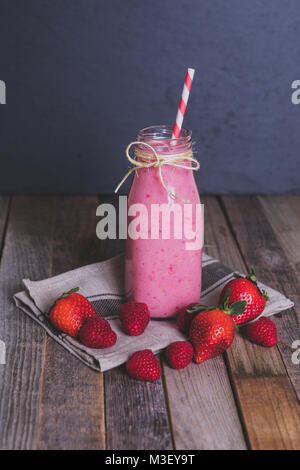 Bicchiere di deliziosi berry smoothie su sfondo di legno. Vista laterale. Foto Stock