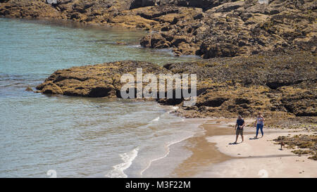 Due persone a piedi il loro cane al Rozel Bay, Jersey, Isole del Canale, REGNO UNITO Foto Stock