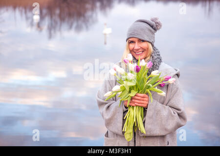 Ritratto di donna bella con i tulipani di fronte al lago Foto Stock