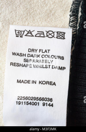 Lavare le istruzioni di cura e i simboli sull'etichetta del capo di abbigliamento abbigliamento made in Corea - piatto secco lavare i colori scuri separatamente mentre cambia forma umida Foto Stock