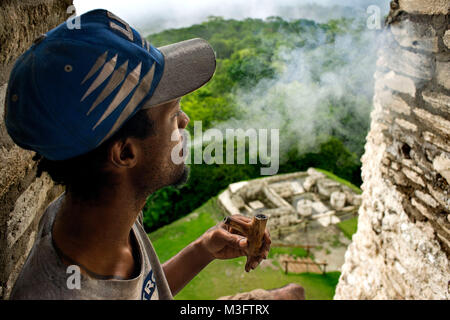 Persone locali fumatori nel tubo in rovine maya di Xunantunich Sito Archeologico vicino a San Ignacio, Belize Foto Stock