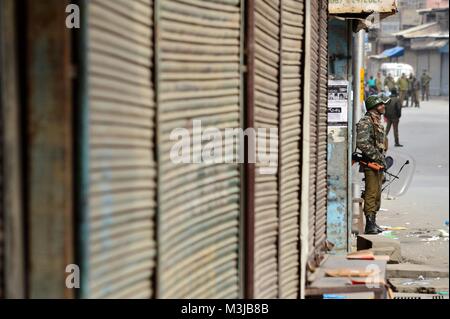 Srinagar, India. Xi Febbraio, 2018. Un indiano soldato paramilitare sta di guardia durante le restrizioni nella vecchia città di Srinagar, India Kashmir amministrato. Coprifuoco-simili restrizioni sono state imposte in parti di Srinagar città al seguito di una chiamata per sciopero dei gruppi separatisti per commemorare l anniversario della morte di Maqbool Bhat, il Jammu e Kashmir Liberation Front (JKLF) fondatore che fu impiccato in Delhi 34 anni fa.In altre parti della vallata, un arresto completo del sistema viene osservata. Negozi, stabilimenti commerciali sono chiusi e molto pochi veicoli sono visibili sulle strade.Maqbool Bhat era hange Foto Stock