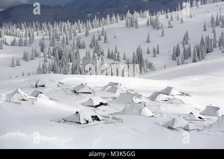 Vista panoramica di coperte di neve cabine di legno e la mountainsat Velika planina, Slovenia. Foto Stock