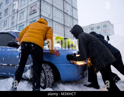 A Murmansk, Russia - 22 Gennaio 2017: persone stanno spingendo al di fuori di un cumulo di neve una vettura bloccato nella neve Foto Stock