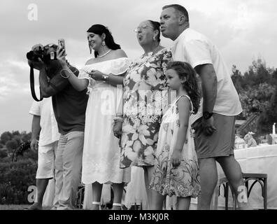 I genitori e la nonna rendendo il viso per cercare di ottenere il bambino ridere o sorridere mentre a un matrimonio in fethiye, Turchia, 4 agosto 2017 Foto Stock