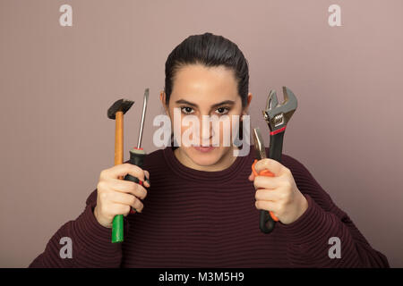 In grado giovane donna in possesso di un set di strumenti nelle sue mani in un concetto di DIY, riparazioni e ristrutturazioni Foto Stock