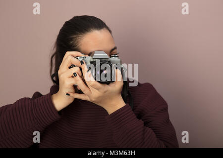 Giovane donna concentrandosi sul visore e di scattare una foto con una fotocamera vintage Foto Stock