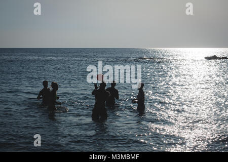 Gallipoli (Italia), Agosto 2017. Un gruppo di giovani giocando a pallavolo in mare al tramonto sulla spiaggia di Padula Bianca. Formato orizzontale. Foto Stock