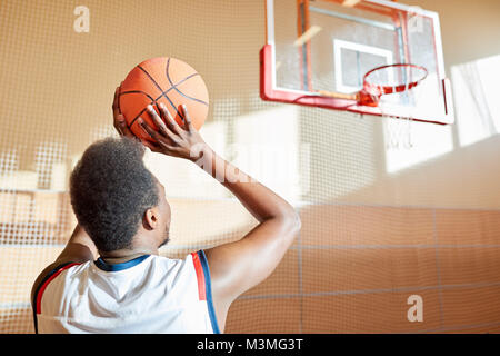 Vista posteriore del determinato giocatore di basket gettando in palla baske Foto Stock
