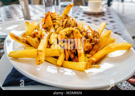 Poutine patatine fritte servite sulla piastra bianca nel ristorante Foto Stock