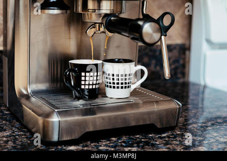 Home macchina espresso sul bancone cucina top facendo due tazze di caffè. Foto Stock
