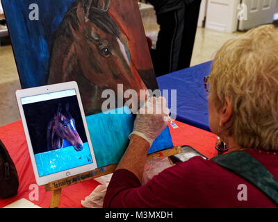 Gli anziani che hanno vissuto una dura ancora rimanere attivi esprimere se stessi nella classe di pittura, Pam Smith utilizza una foto scattata con il suo iPad a dipingere un cavallo di amici. Foto Stock