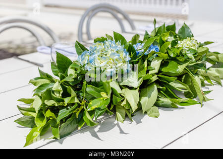 Tavolo bianco con Hortensia mazzo di fiori per un matrimonio impostato. Sedie bianche sullo sfondo. Foto Stock