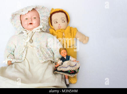 Gruppo di tre bambole antiche su sfondo bianco