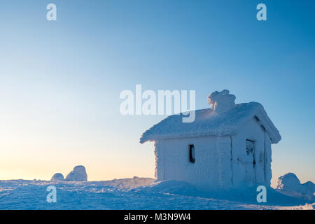 Una neve incrostati di cabina sulla cima di una collina in Finlandia Foto Stock