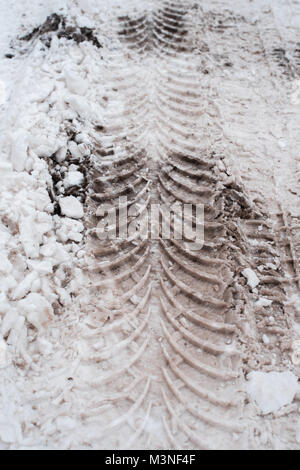 Close-up di sporco di neve in inverno nella città. Le tracce delle ruote delle auto del battistrada sulla neve. Foto Stock