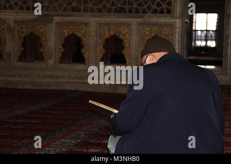 Il vecchio uomo che legge il sacro Corano in una moschea Foto Stock