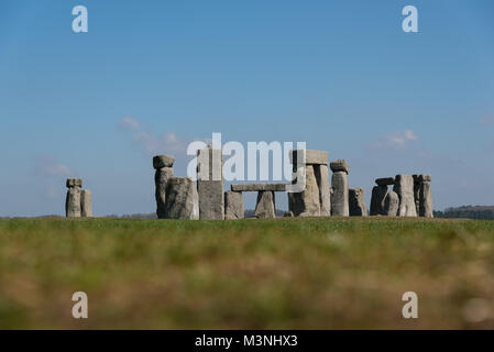 Stonehenge, Wiltshire - vista attraverso i campi di erba dei circoli di pietre su una tranquilla giornata con n. di visitatori - primo piano sfocato Foto Stock