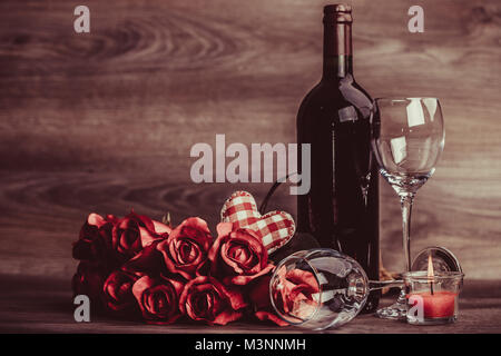 Rosso bottiglia di vino, due bicchieri di vino, rose con decorazione dal cuore rosso sul tavolo di legno. Valentines Day celebrazione del concetto. Copia dello spazio. Foto Stock