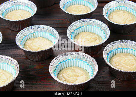 L'impasto negli stampi per muffin su una tavola di legno Foto Stock