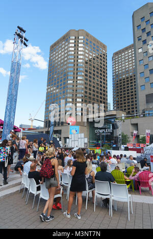 Pubblico in attesa di un spettacolo all'aperto per iniziare sulla Place des Festivals in Montreal, provincia del Québec in Canada. Foto Stock