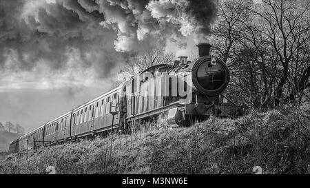 Un bianco e nero mono vicino la fotografia di un treno a vapore locomotiva e carrozze fumatori e da un basso angolo di visione Foto Stock
