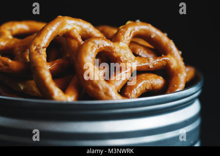 Pretzel croccanti stuzzichini in un vaso di metallo su sfondo nero. Macro shot. Foto Stock